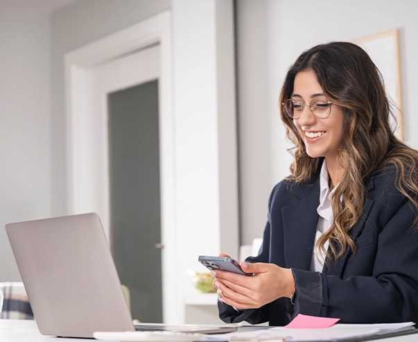 Mujer usando teléfono y computadora.